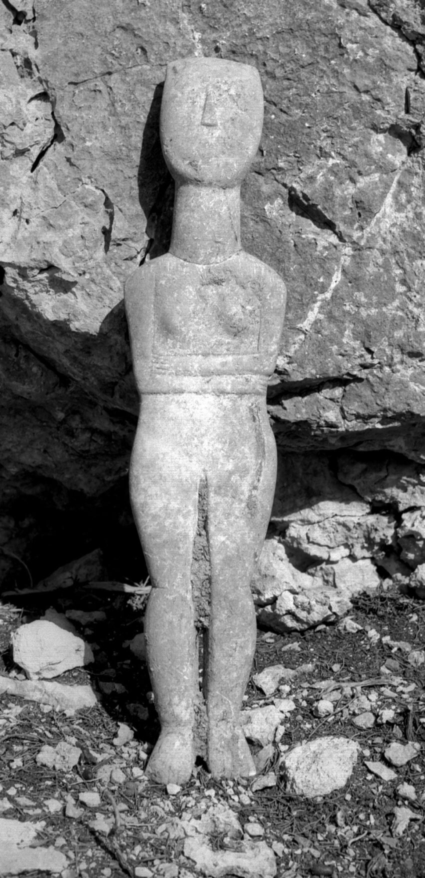 Grayscale image of a Cycladic figure with her arms wrapped around her waist