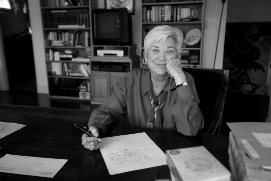 Black-and-white photo of Ellen Bryant Voigt writing at her desk in 2015