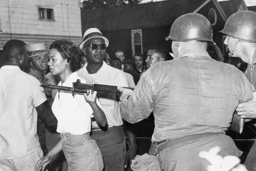 The activist Gloria Richardson walking past National Guardsmen during a civil rights march in Cambridge