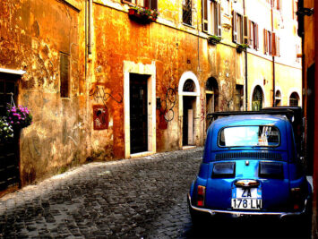 Cobblestone street with blue car and stone buildings. Mozzercork / Creative Commons