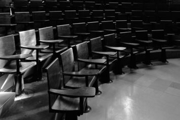 Black and white photograph of lecture hall desks in a semi-circle